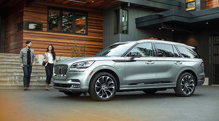A man and woman standing near a car outside a house