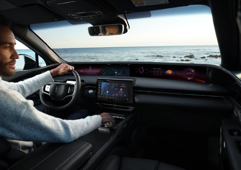 A driver of a parked 2024 Lincoln Nautilus® SUV takes a relaxing moment at a seaside overlook while inside his Nautilus. | Lincoln of Cutler Bay in Miami FL