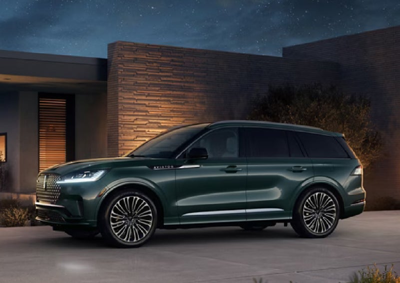 A green 2027 Lincoln Aviator® SUV is parked outside a contemporary home. | Lincoln of Cutler Bay in Miami FL