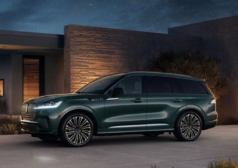 A green 2027 Lincoln Aviator® SUV is parked outside a contemporary home. | Lincoln of Cutler Bay in Miami FL