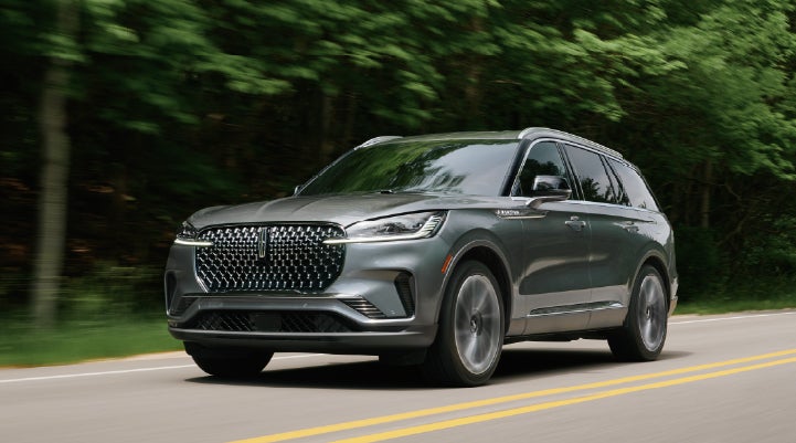 A 2027 Lincoln Aviator® SUV is being driven down a road lined with trees. | Lincoln of Cutler Bay in Miami FL