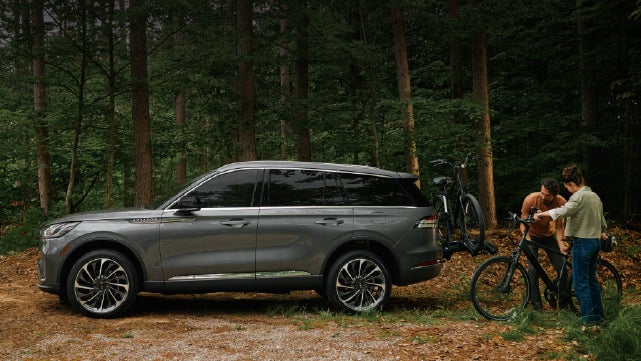 A father and son load e-bikes on a bike rack attached to a 2027 Lincoln Aviator® SUV. | Lincoln of Cutler Bay in Miami FL