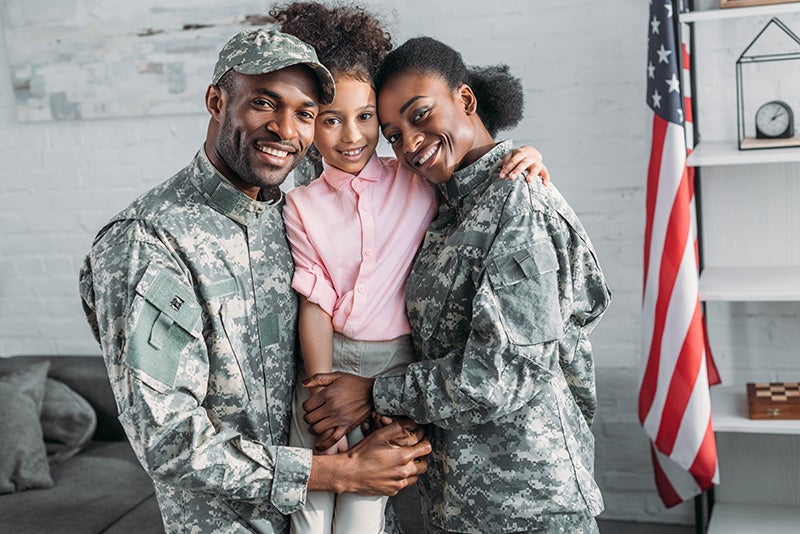 A military family in uniform holding their child